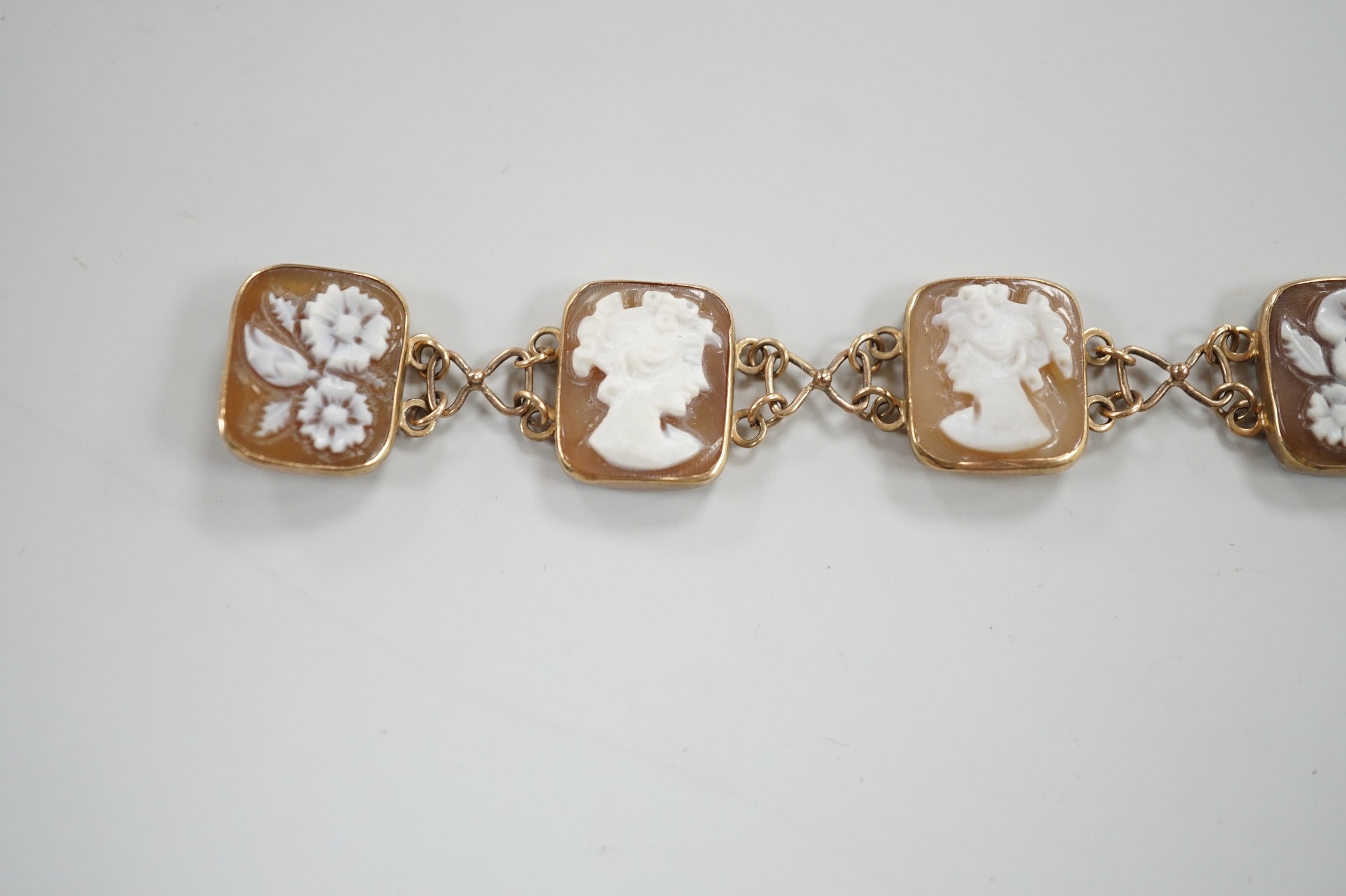 A 1970's 9ct gold and seven cameo panel set bracelet, carved with busts of ladies or flowers, 18cm, gross weight 10.3 grams.